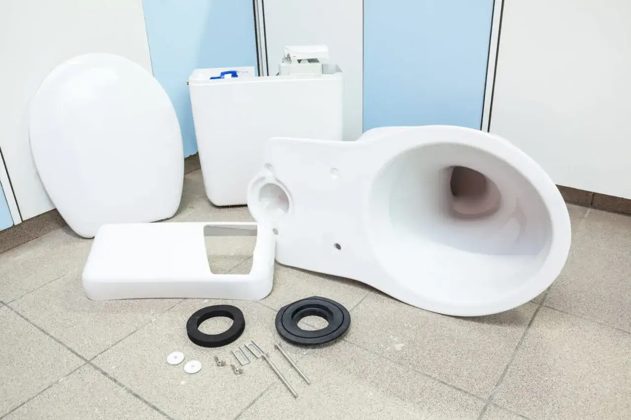 Pièces d'un nouveau WC blanc démontées sur le sol, prêtes pour le schéma d'installation.