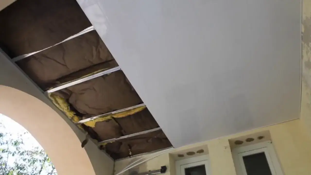 Pose lambris PVC plafond en cours, isolant visible sous les lames blanches. Travaux de r&eacute;novation en cours.