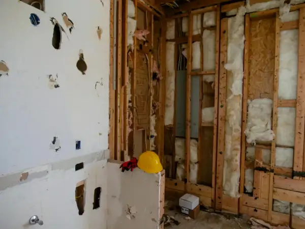 Chantier en cours, murs ouverts révélant l'isolant. Attention, la laine de bois peut présenter un danger si mal manipulée. Casque et gants de protection à proximité.