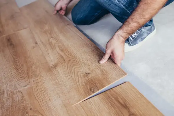Pose d'un parquet stratifié imitation bois. Un homme installe une lame de revêtement de sol.