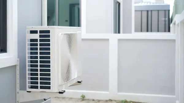 Unité extérieure de pompe à chaleur installée sur un mur blanc, prête à assurer le confort de la maison.