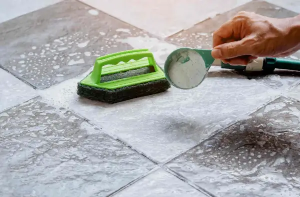 Nettoyer carrelage mural encrassé avec une éponge verte et une poudre nettoyante.