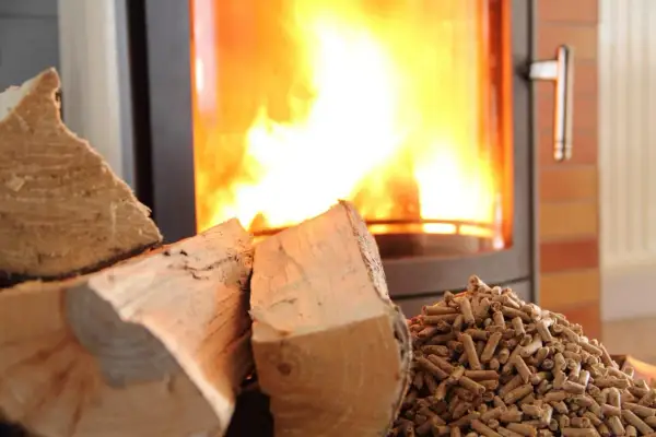 Bûches et granulés de bois prêts pour le chauffage. Le feu crépite dans le poêle, promettant une douce chaleur.