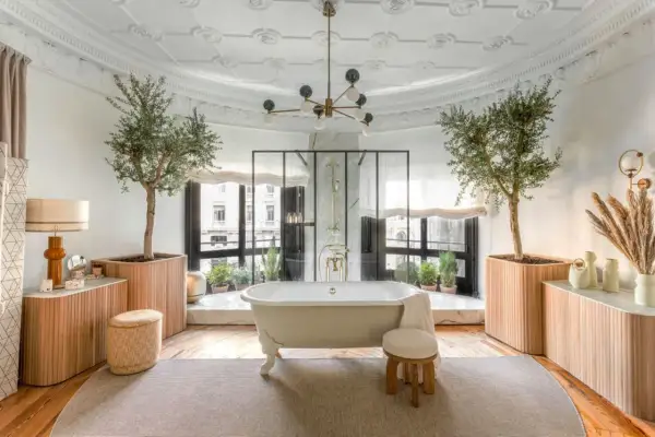 Salle de bain luxueuse avec baignoire îlot, arbres d'olivier et vue sur la ville. L'évacuation baignoire îlot est discrète.