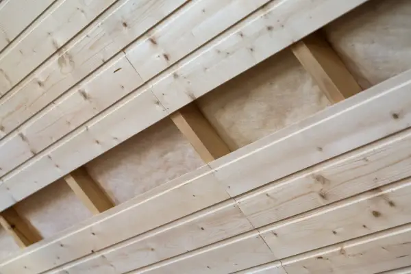 Pose lambris en bois clair, montrant la structure sous-jacente avec des tasseaux et de l'isolant.