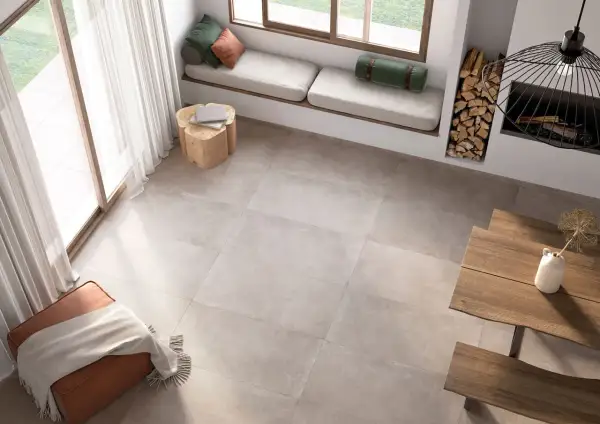 Un salon lumineux avec un **schema plancher bois** discret, un banc près de la fenêtre, un pouf et une table en bois.