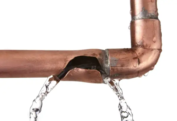Une fuite sur un tuyau en cuivre provoque un jet d'eau. L'eau s'échappe d'une fissure béante dans le métal.