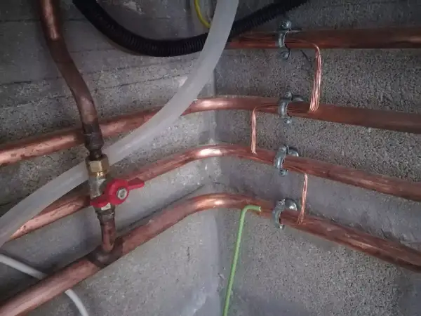 Système de tuyauterie en cuivre avec mise à la terre. Des fils de cuivre sont fixés aux tuyaux pour assurer la mise à la terre.
